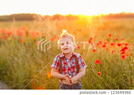 A funny young boy with eye misalignment, smiling and giggling in a sunset-lit poppy field A funny young boy with eye misalignment, smiling and giggling in a sunset-lit poppy field 123649360