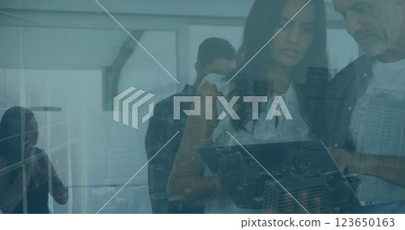 Image of diverse colleagues using tablet in office over cityscape 123650163