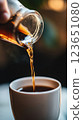 close up of coffee being poured from glass jar into white cup, capturing rich color and texture of beverage. warm tones create cozy atmosphere 123651080