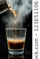 Rich coffee pouring into glass, steam rising, creating warm atmosphere 123651106