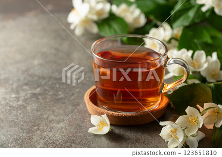 Herbal tea and blooming jasmine branch on a stone table. 123651810
