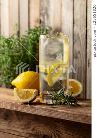 Summer refreshing drink with ice, rosemary and lemon slices on a old wooden table. Summer refreshing drink with ice, rosemary and lemon slices on a old wooden table. 123651820