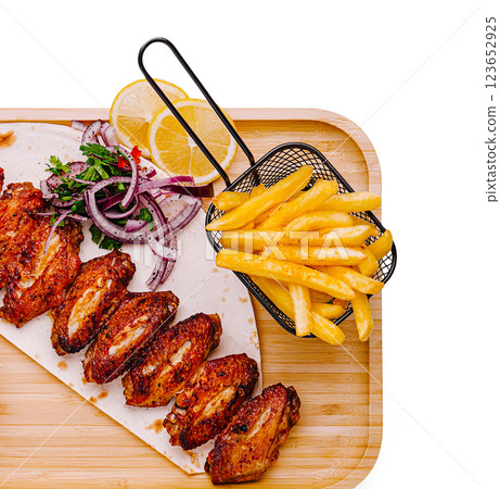 Crispy chicken wings served with fries and fresh lemon slices 123652925