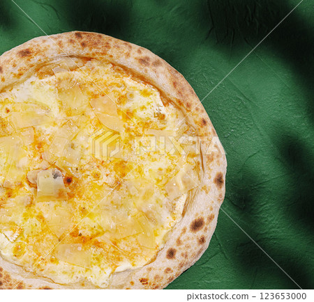 Pizza topped with cheese and pineapple on a green background 123653000
