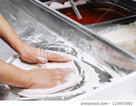 Preparing dough for pizza at a busy countertop kitchen Preparing dough for pizza at a busy countertop kitchen 123653002