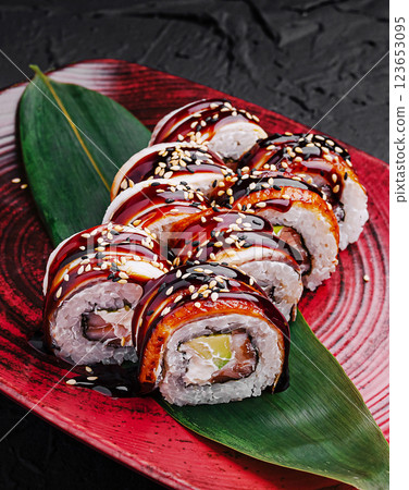 Delicious sushi rolls with glossy sauce served on a red plate Delicious sushi rolls with glossy sauce served on a red plate 123653095