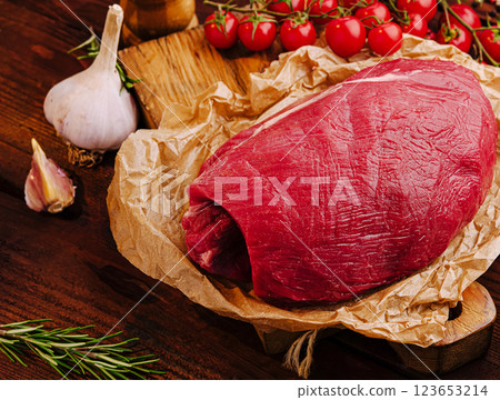 Fresh raw beef surrounded by garlic and cherry tomatoes on wood Fresh raw beef surrounded by garlic and cherry tomatoes on wood 123653214
