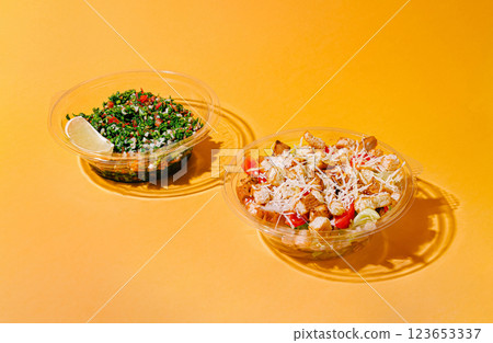 Fresh salad and hearty meal on a bright yellow backdrop Fresh salad and hearty meal on a bright yellow backdrop 123653337