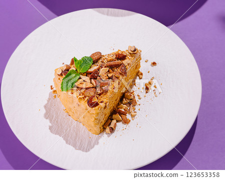 Delicious slice of cake with almonds and mint on white plate 123653358