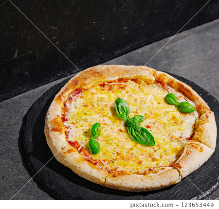 Freshly baked cheese pizza with basil on a stone platter Freshly baked cheese pizza with basil on a stone platter 123653449
