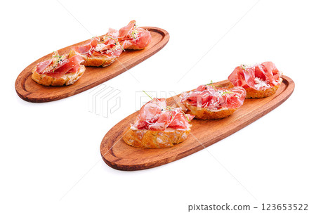 Delicious tapas featuring cured ham on wooden serving boards 123653522