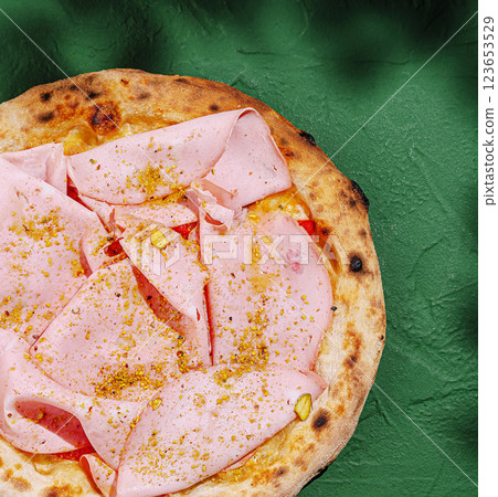 Delicious pizza topped with ham and pistachios served on a green table 123653529