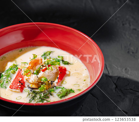 Delicious seafood soup served in a red bowl with garnishes Delicious seafood soup served in a red bowl with garnishes 123653538