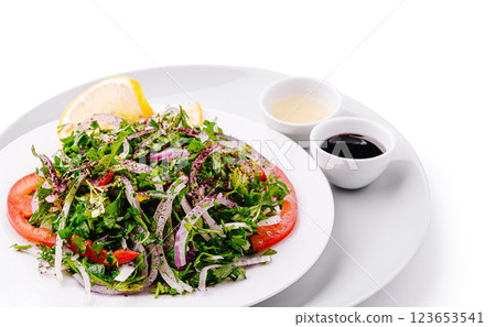 Fresh green salad with lemon and dressings on a white plate 123653541