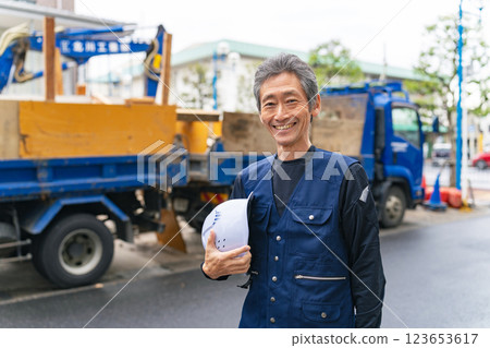 一位工匠微笑著站在建築工地前 123653617