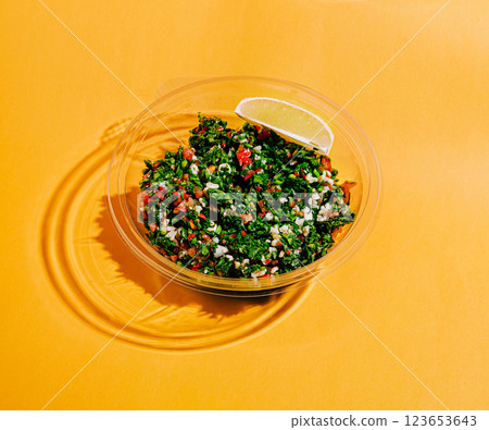Fresh tabbouleh salad with lemon slice on vibrant background Fresh tabbouleh salad with lemon slice on vibrant background 123653643