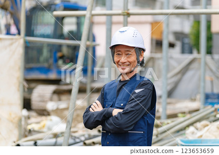 A craftsman standing in front of a construction site with a smile 123653659