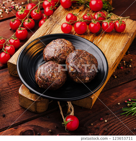 Savory meatballs served on a wooden board with fresh tomatoes 123653711