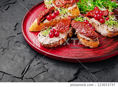 Delicious bruschetta topped with sun-dried tomatoes and sprouts 123653737