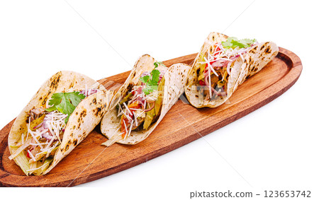 Delicious tacos served on a wooden platter with fresh ingredients 123653742