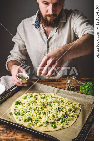 Man cooks pizza with broccoli and pesto sauce 123654367