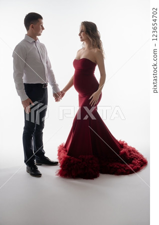 Couple joyfully celebrating pregnancy in elegant red attire 123654702