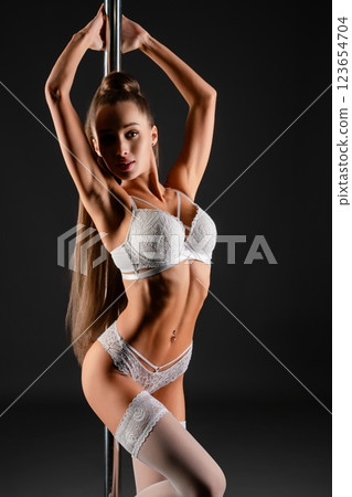 Woman performing an elegant dance around a pole in stylish lingerie indoors 123654704