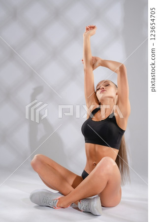 Woman stretching in athletic wear during indoor workout session 123654705