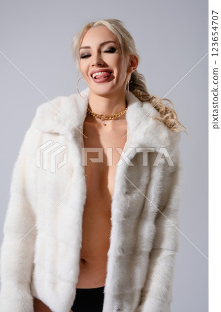 Woman poses confidently in white lingerie and fur coat for fashion shoot 123654707