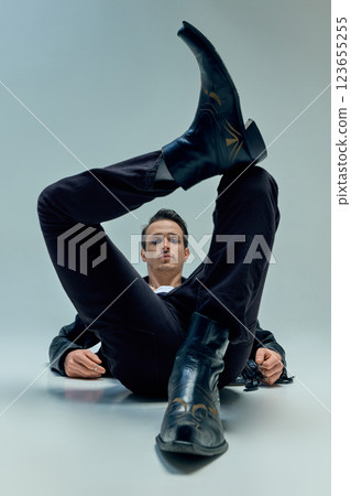 Dramatic perspective capturing musician lying, boot dominating foreground in bold framing against clean background. Dramatic perspective capturing musician lying, boot dominating foreground in bold framing against clean background. 123655255