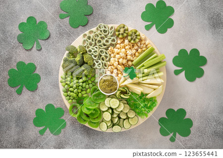 St Patricks day with vegetables charcuterie board and traditional green clover leaves on gray background. Festive holiday appetizer for celebration. Top view 123655441