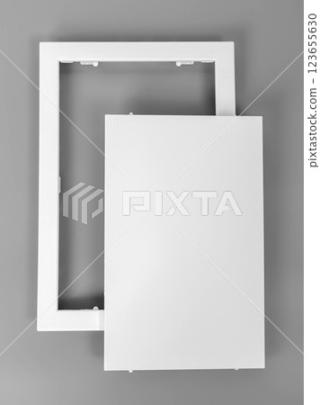 White plastic hatch on a gray background. Rectangular shape. Door for access to the pipes. 123655630