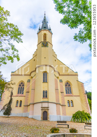 The Church of St. Joachim stands elegantly in Jachymov, Czechia, showcasing its architectural beauty amidst lush greenery and cloudy skies. Visitors admire the historic structure. The Church of St. Joachim stands elegantly in Jachymov, Czechia, showcasing its architectural beauty amidst lush greenery and cloudy skies. Visitors admire the historic structure. 123655953