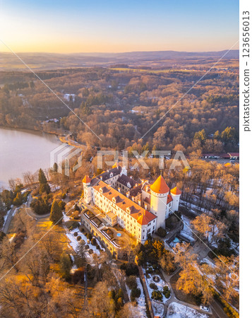 This stunning aerial view captures Konopiste Castle, surrounded by lush forests and a serene lake. The warm glow of sunset highlights the castle's unique architecture and vibrant rooftops. This stunning aerial view captures Konopiste Castle, surrounded by lush forests and a serene lake. The warm glow of sunset highlights the castle's unique architecture and vibrant rooftops. 123656013