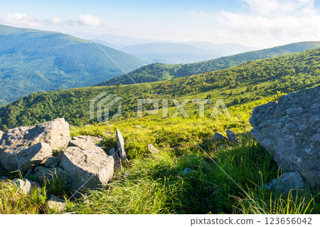 rolling landscape with stones on the grassy slope. sunny morning. beautiful alpine scenery of carpathian mountain smooth in summer. clouds on the bright blue sky. scenic view in to the distant valley 123656042