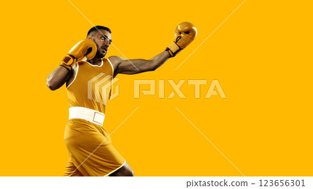 Sport collage. Young boxer wearing in gold landing powerful punch, intensity and confidence reflected in every move. Bold yellow colors. Sport collage. Young boxer wearing in gold landing powerful punch, intensity and confidence reflected in every move. Bold yellow colors. 123656301
