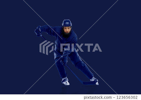 Sport collage. Focused, female ice hockey player in deep blue charging forward, stick guiding action on monochrome background. Sport collage. Focused, female ice hockey player in deep blue charging forward, stick guiding action on monochrome background. 123656302