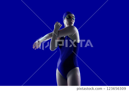 Creative collage. Swimmer in deep blue suit stretching, preparing for race, and background amplifying energy. Concept of professional sport Creative collage. Swimmer in deep blue suit stretching, preparing for race, and background amplifying energy. Concept of professional sport 123656309