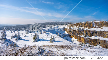 The snow-covered Stanislaw Quartz Mine is nestled in the Izerskie Garby of the Izera Mountains. The landscape features frosted trees, rocky outcrops, and a serene winter sky. 123656540