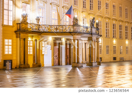 The ornate entrance to Prague Castle reveals a balcony adorned with statues, illuminated by soft lights in the evening. The tranquil courtyard reflects the beauty of the historic site. The ornate entrance to Prague Castle reveals a balcony adorned with statues, illuminated by soft lights in the evening. The tranquil courtyard reflects the beauty of the historic site. 123656564