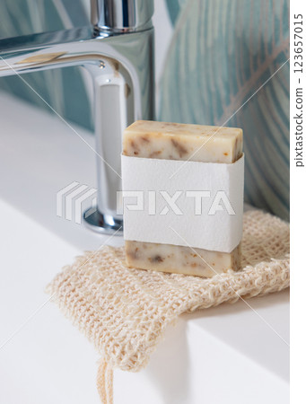 Beige handmade soap bar with blank label on soap saver bag on washbasin close up, mockup Beige handmade soap bar with blank label on soap saver bag on washbasin close up, mockup 123657015