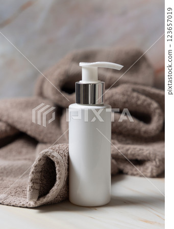 White blank one pump cream bottle near brown bath towel closeup, mockup. Natural herbal cosmetic White blank one pump cream bottle near brown bath towel closeup, mockup. Natural herbal cosmetic 123657019