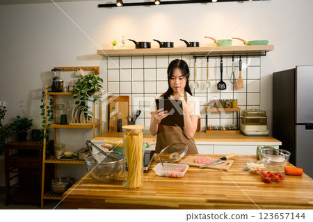 Happy young woman following cooking tutorial on digital tablet while preparing a spaghetti 123657144