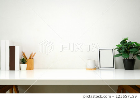 Modern workspace with books, a cup of coffee, blank picture frame, and a potted plant Modern workspace with books, a cup of coffee, blank picture frame, and a potted plant 123657159