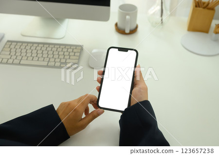 Close up of businesswoman holding smartphone with white screen sitting at workplace Close up of businesswoman holding smartphone with white screen sitting at workplace 123657238