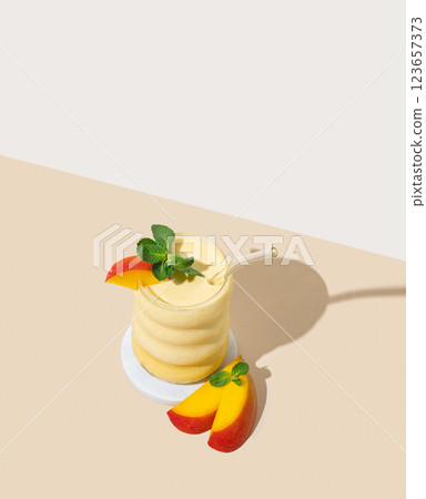 Frozen smoothie with mango and banana in a glass on a yellow background with fruits and shadow. 123657373