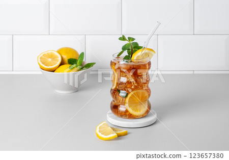 Iced tea with lemon, ice and mint in a glass on the kitchen countertop with citrus fruits 123657380