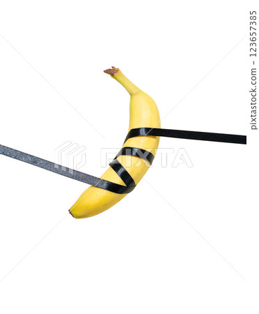 Ripe banana tied with a black ribbon on a white isolated background. Ripe banana tied with a black ribbon on a white isolated background. 123657385