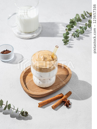 Dalgona coffee in a glass on a light background with shadow and spices. 123657386