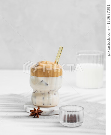 Dalgona coffee in a glass on a light background with milk jug and spices. 123657391